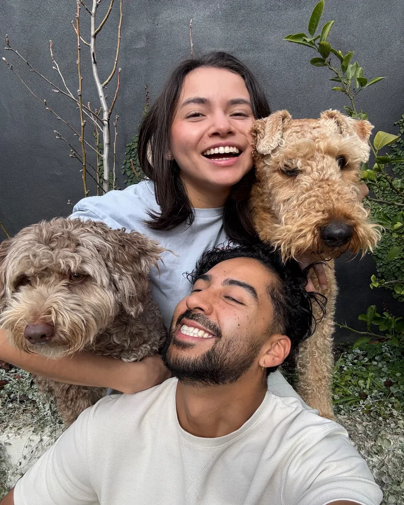 Yen and Nico taking a selfie with a brown curly dog and an apricot curly dog