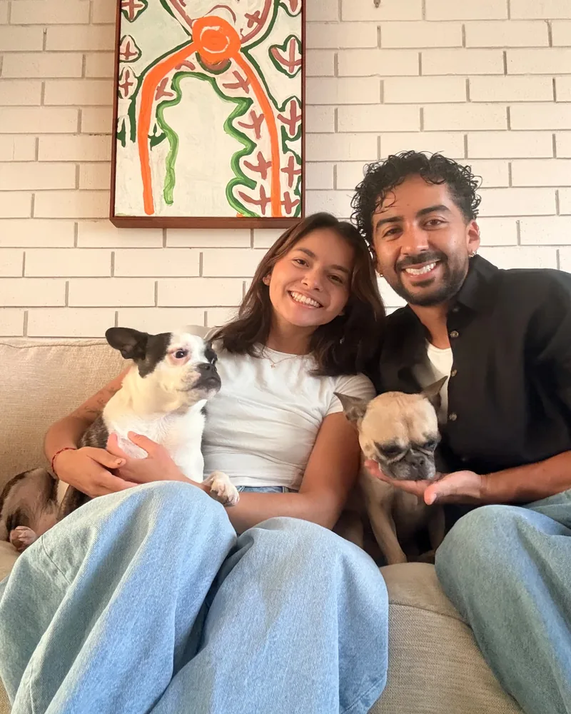 Yen and Nico sitting on a sofa with a boston terrier and a fawn french bulldog