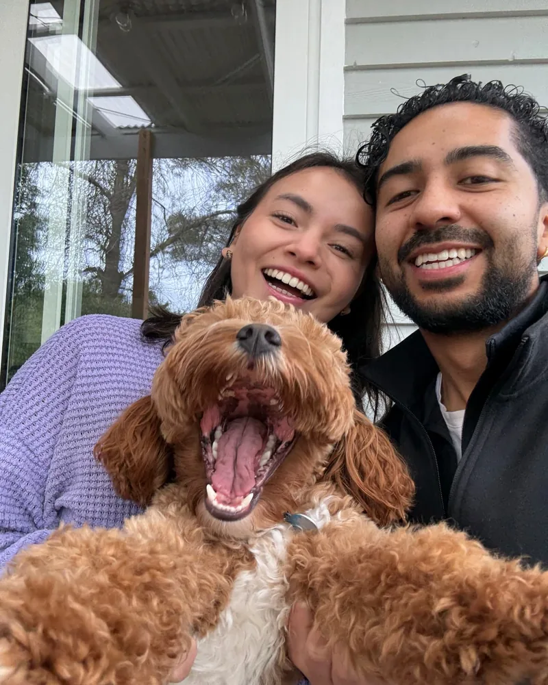 Yen and Nico taking a selfie with a yawning apricot cavoodle